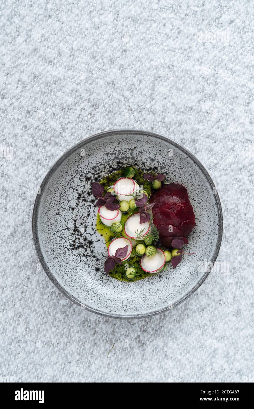 Beautiful grey bowl with mixed chopped potherbs, peas and vegetables served on grey textured?cloth from above Stock Photo