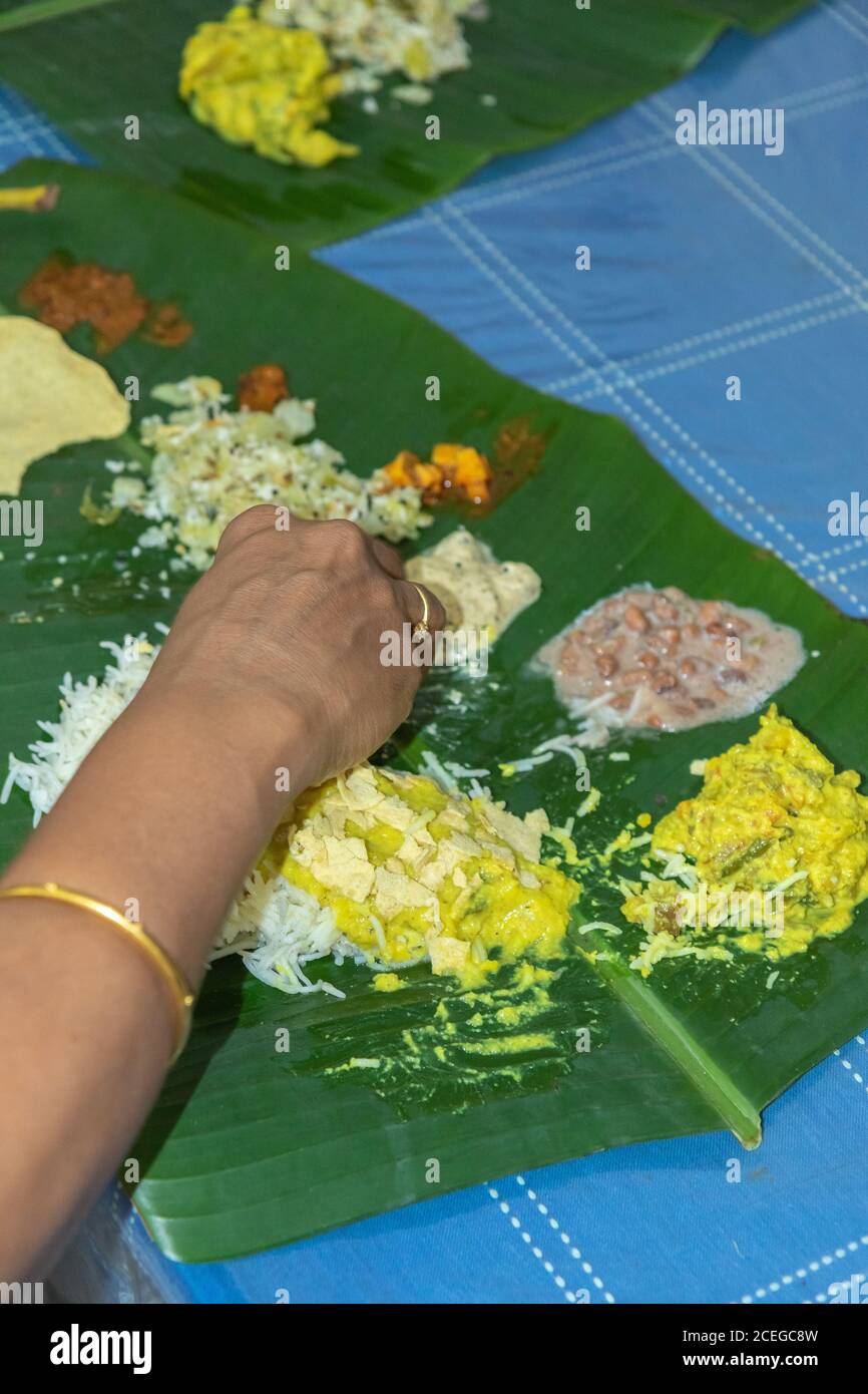 Traditional Kerala food being eaten on a banana leaf during the Onam festival in Kerala India Stock Photo