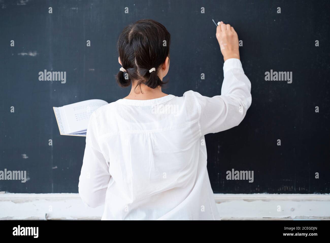 Teacher at the blackboard writing the lesson. Back to school concept ...