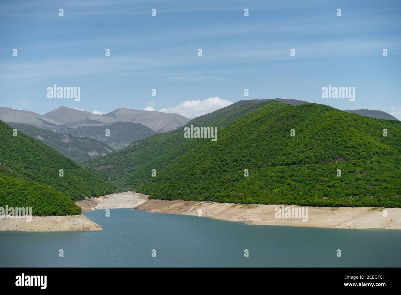 Panoramic view of green mountains lying around old city and river confluence with road nearby on sunny summer day Stock Photo