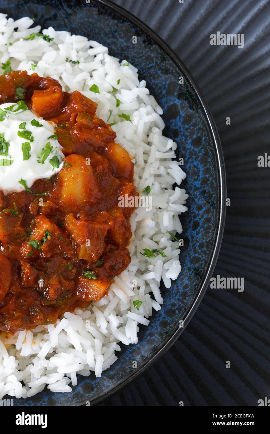 vegetarian meal, vegetable and butter bean chilli with rice in a dark blue bowl Stock Photo