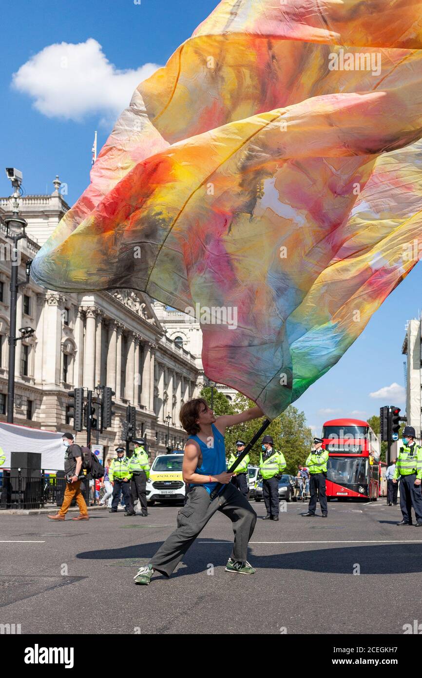 A young male Extinction Rebellion protester waves a huge flag outside Parliament during the 2020 demonstrations. UK Stock Photo
