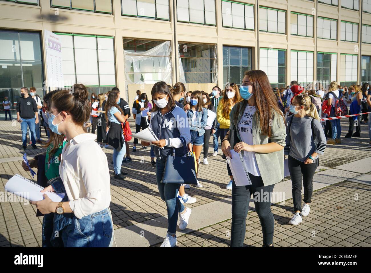 Students queuing at the school entrance wearing mask face to prevent infection or respiratory illness. Turin, Italy - September 2020 Stock Photo