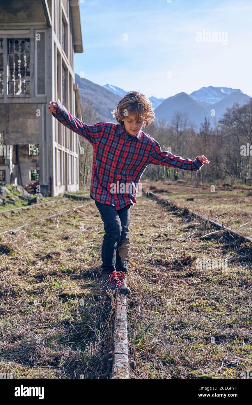 Little child in casual wear with hands to sides near rail tracks ...
