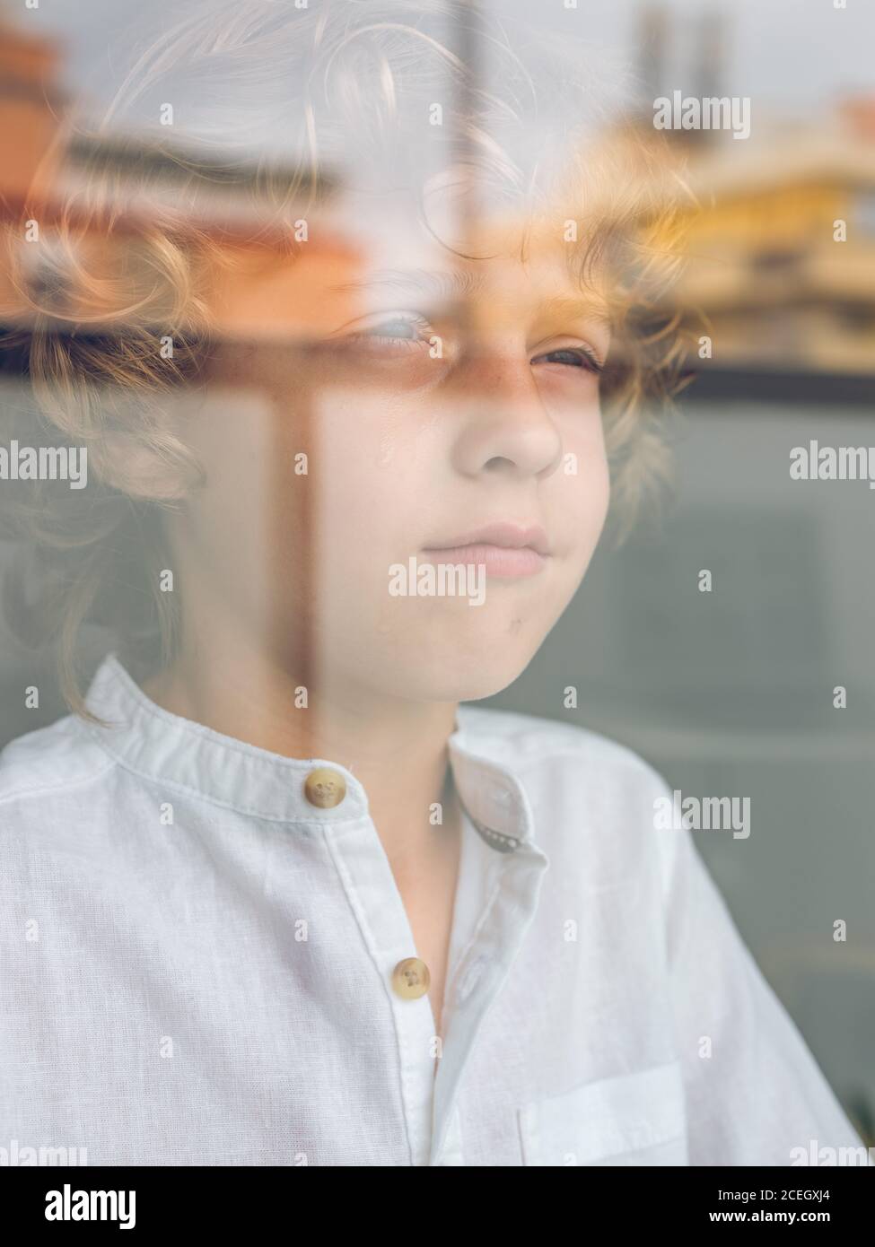 Sad little boy looking through glass Stock Photo
