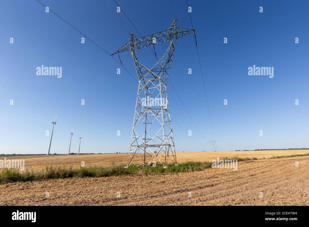 High voltage electricity tower and wind farm under blue sky Stock Photo ...