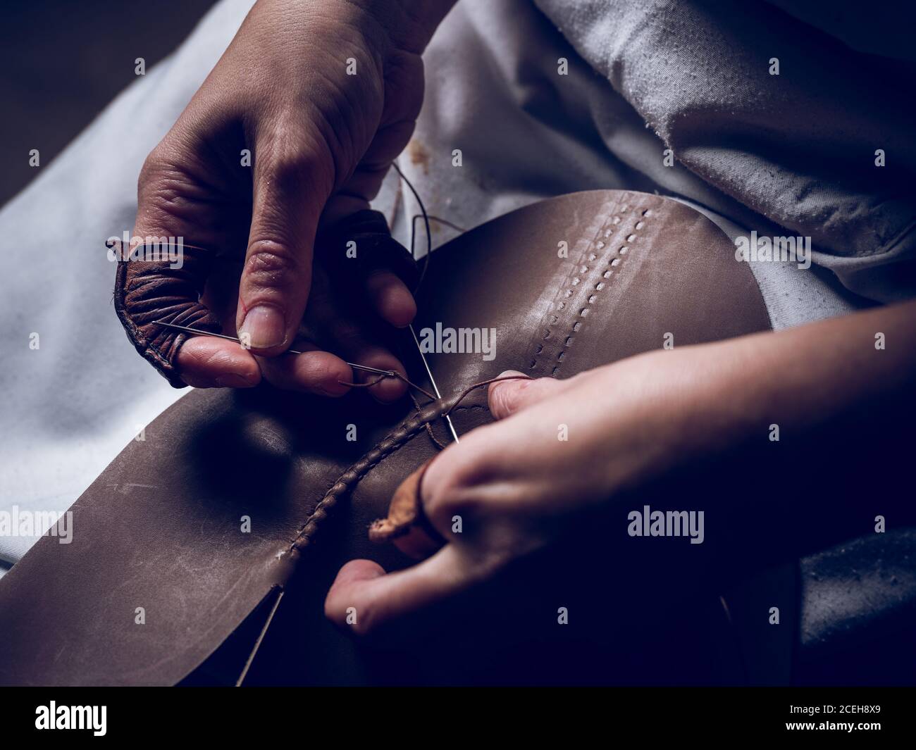 Crop hands stitching leather for shoes Stock Photo
