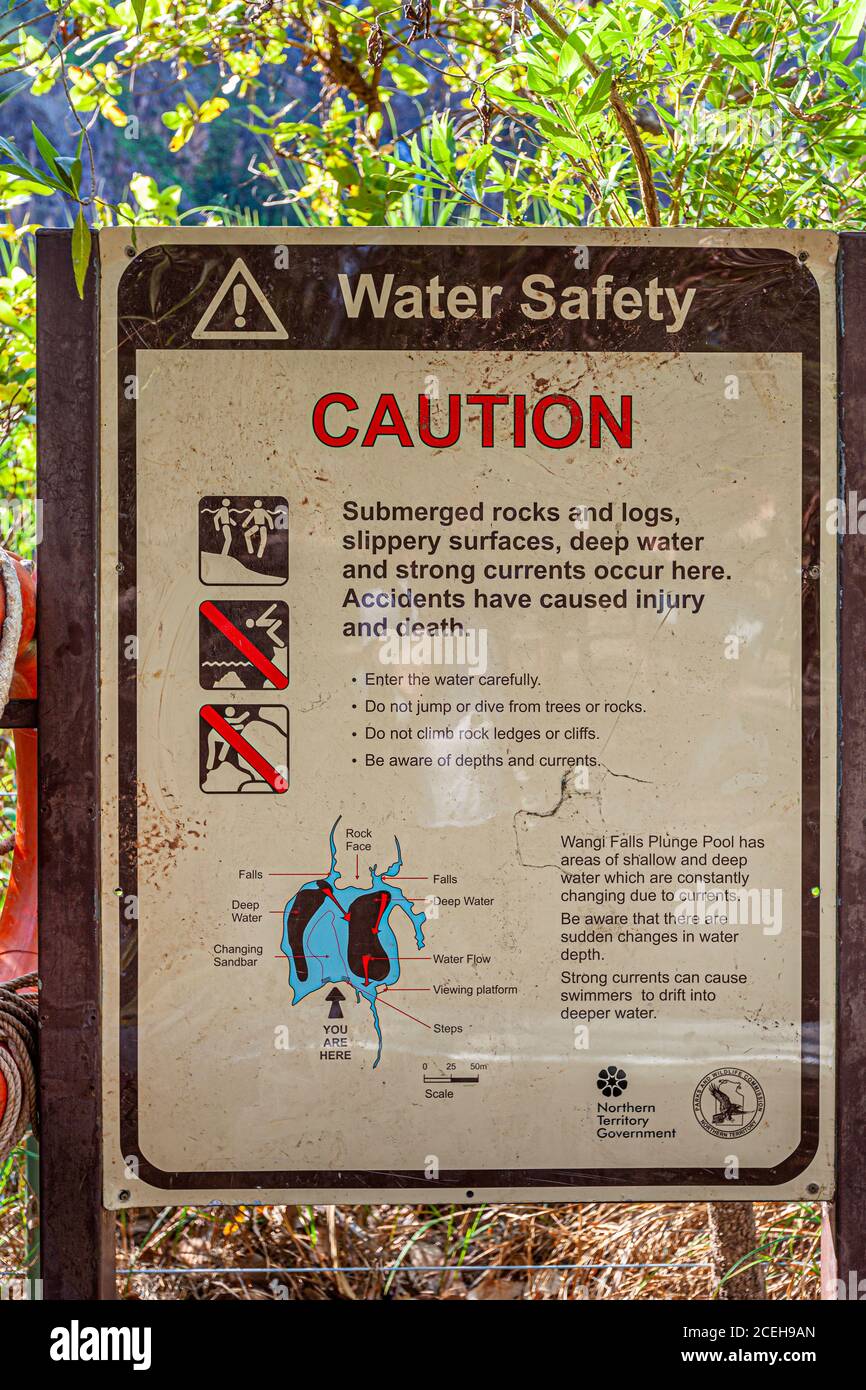A "Water Safety" warning sign at the Wangi Falls plunge pool in Litchfield National Park, Northern Territory, details hazards from submerged rocks, currents and changing water depths. A map marks the falls, walkways and the viewer's own position. Stock Photo