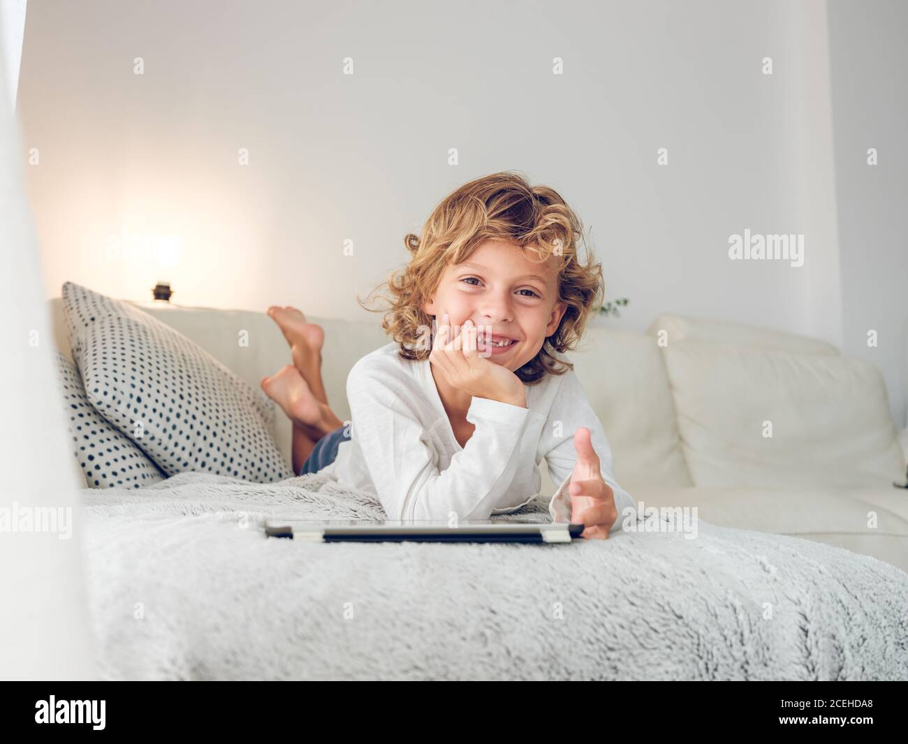 Cheerful boy using tablet of couch Stock Photo