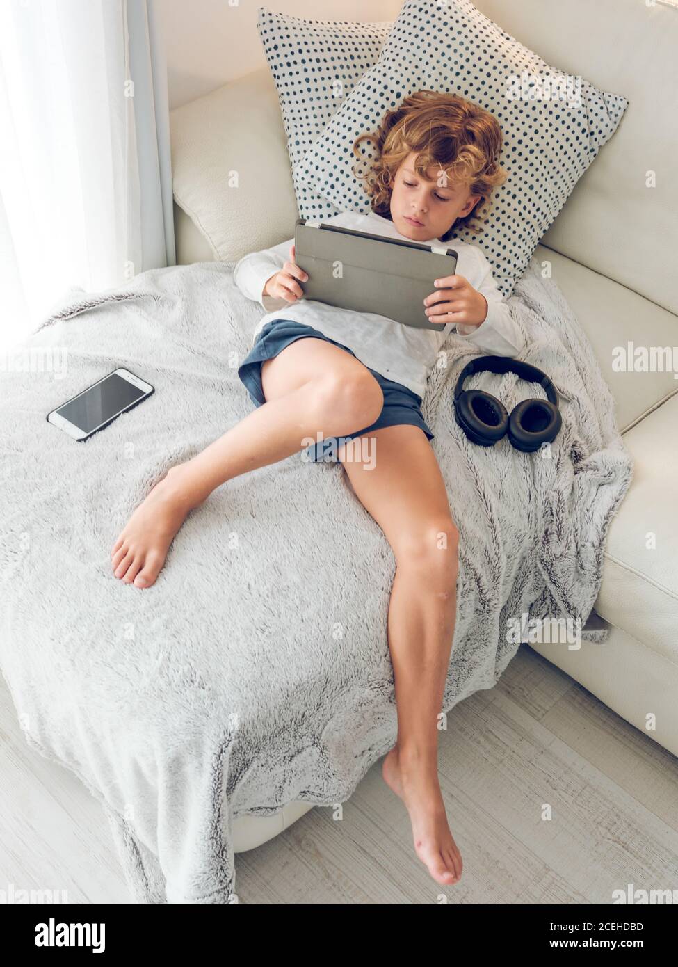 Cheerful boy using tablet of couch Stock Photo