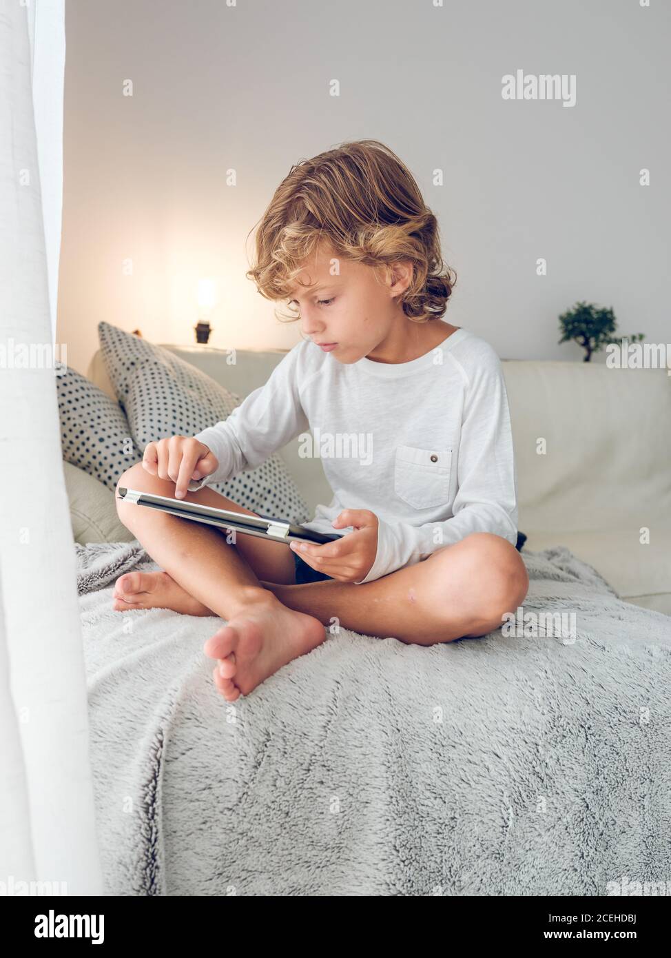 Cute boy with tablet on sofa Stock Photo
