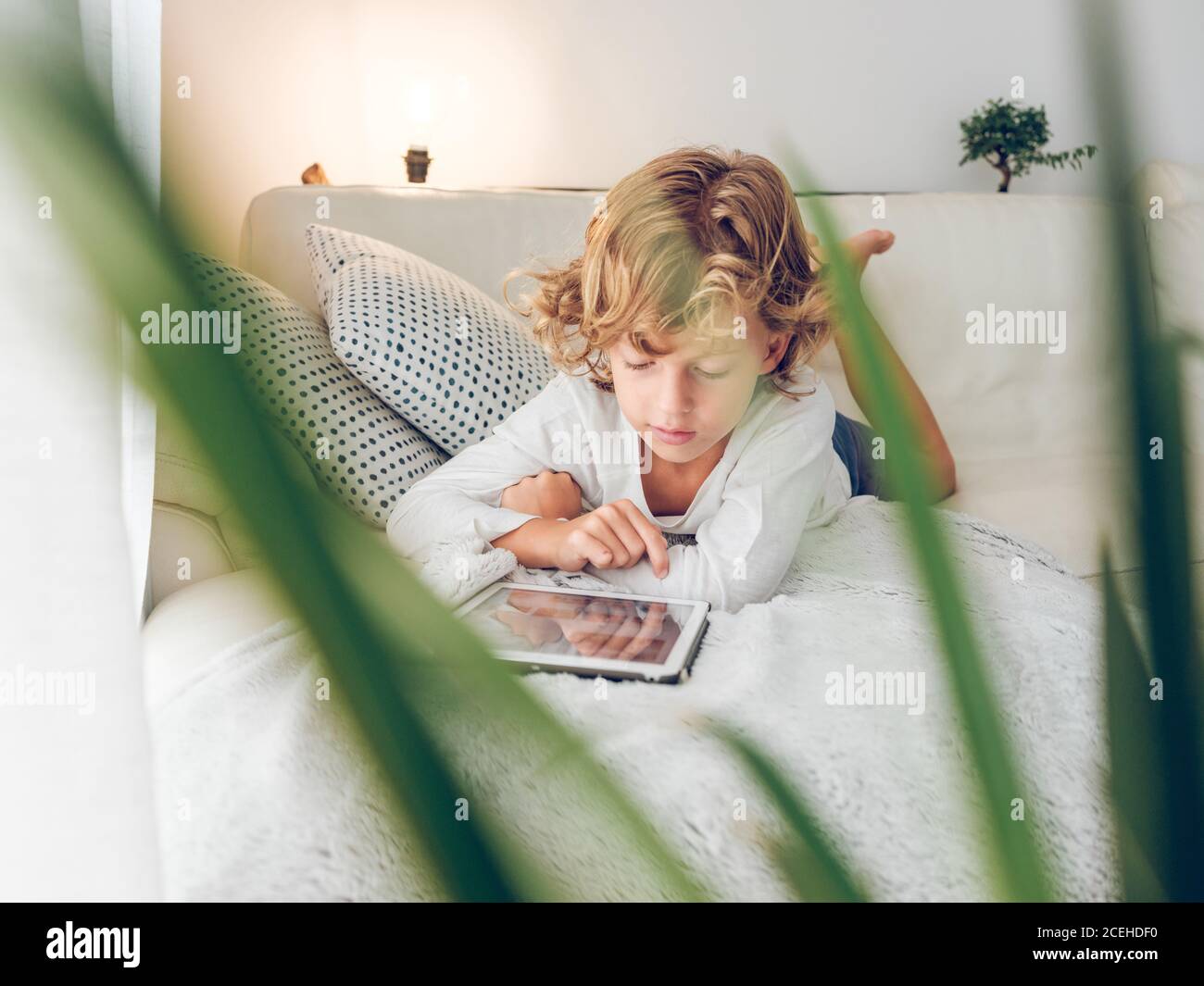 boy using tablet on sofa Stock Photo