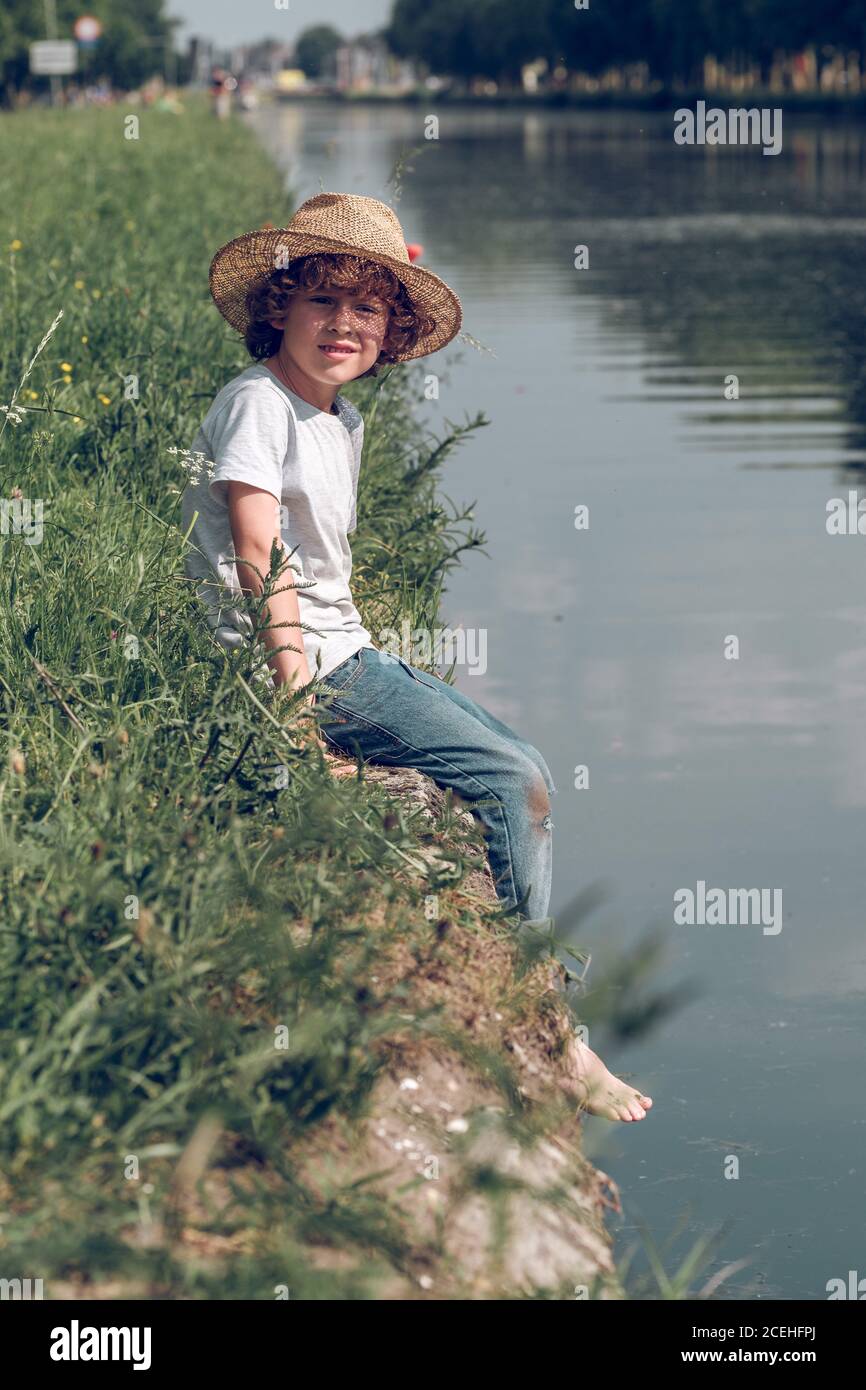 Little boy swinging legs above water Stock Photo Alamy