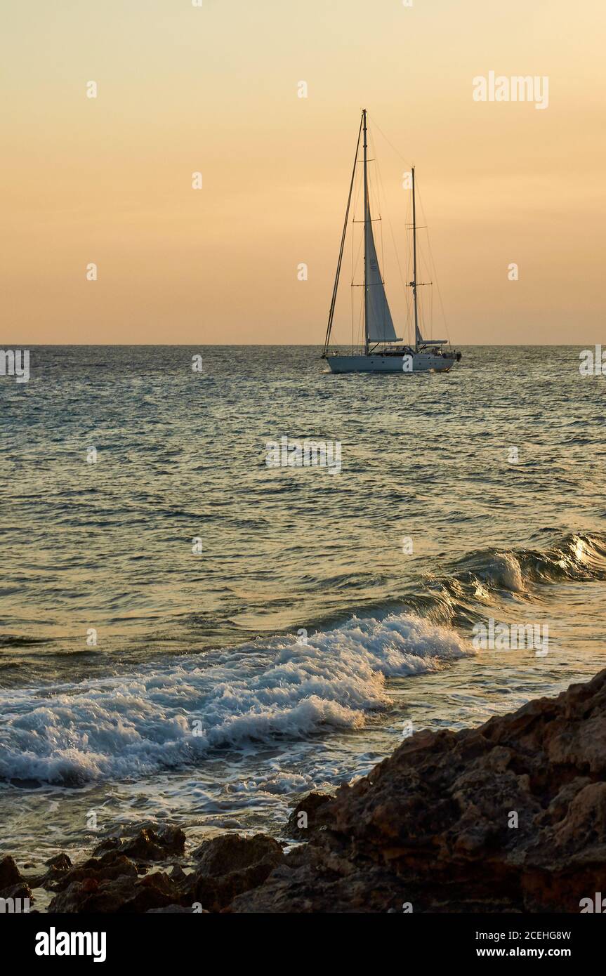 Sailing ship near Cap de Ses Salines coastline at sunset (Santanyí, Majorca, Balearic Islands, Mediterranean sea, Spain) Stock Photo