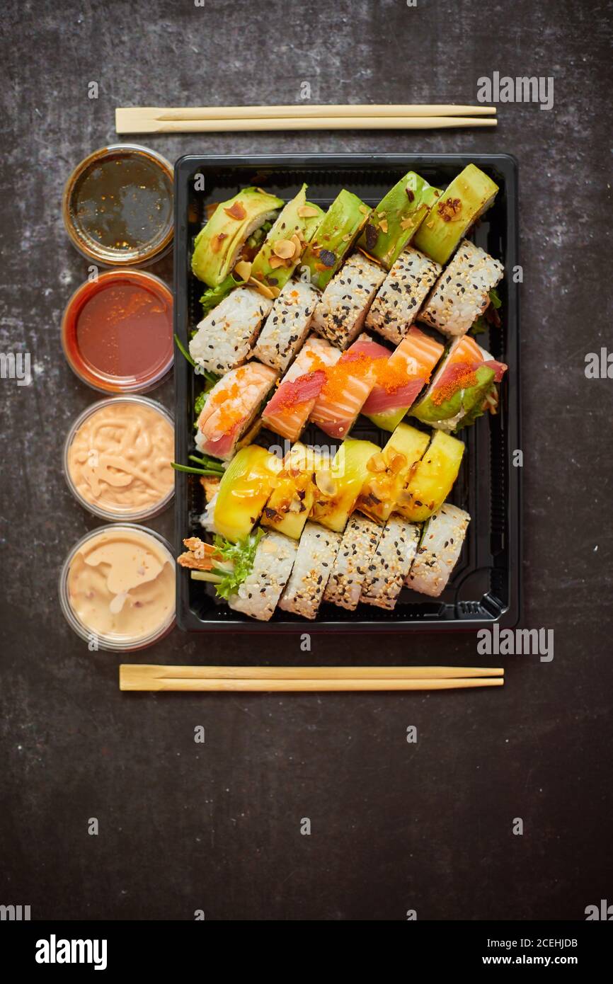 Asian food delivery home, various sushi sets in plastic containers with sauces, rice and chopsticks Stock Photo