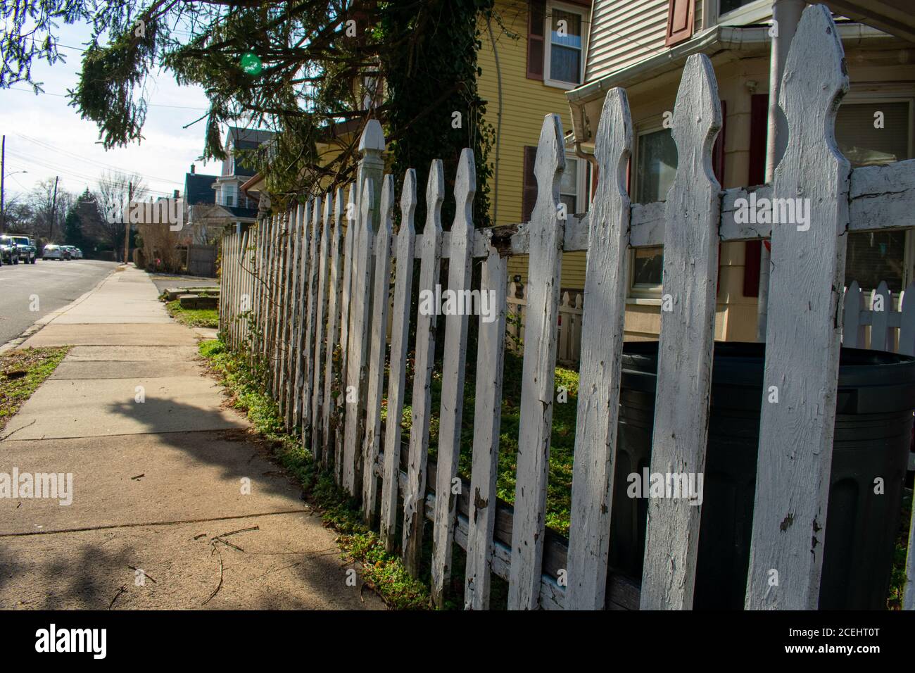 An Old Weathered and Broken White Wooden Fence on a Suburban Street Stock Photo