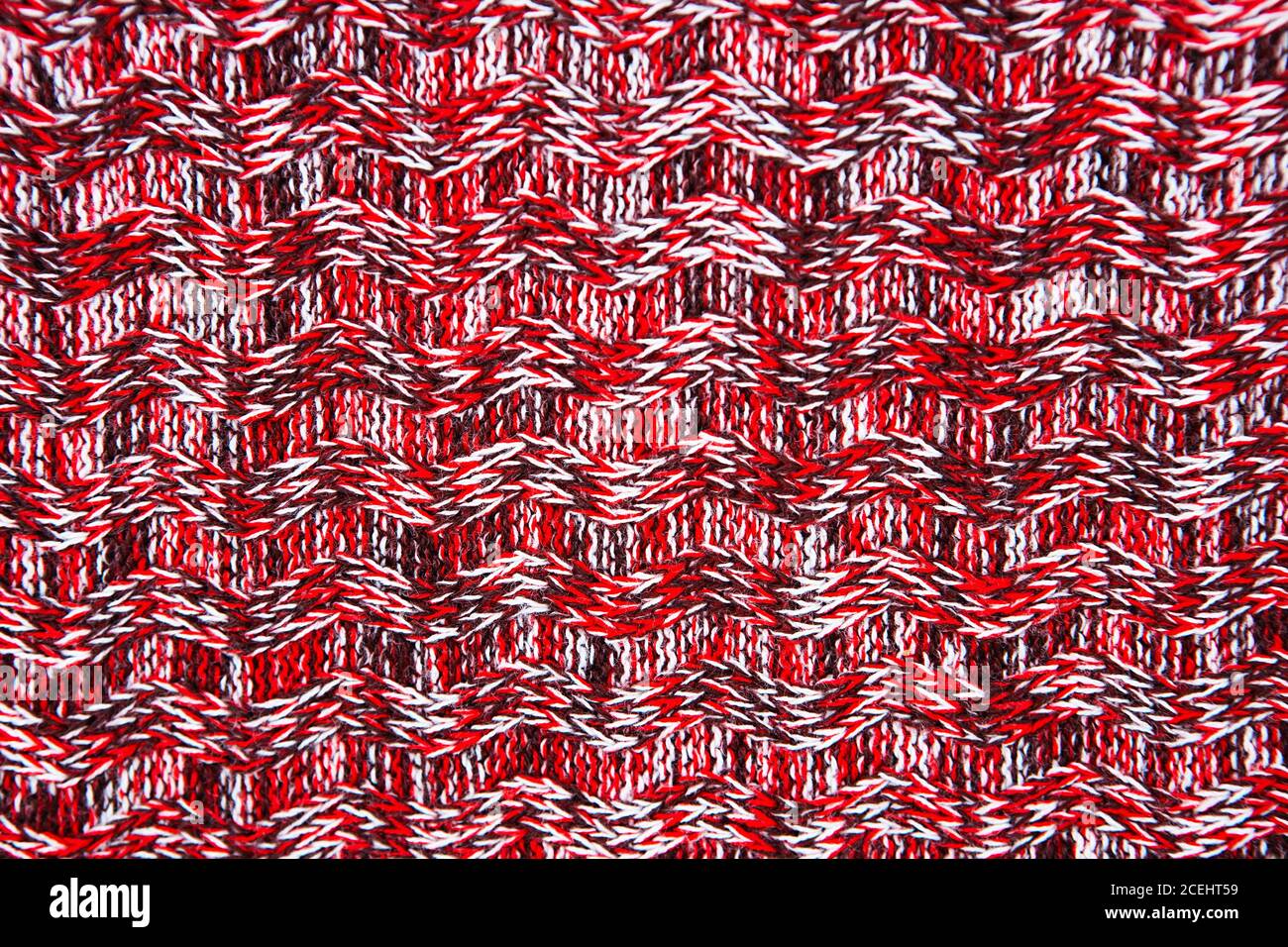 Wool scarf or sweater texture close up. Red Knitted jersey background with a relief pattern. Braids in machine knitting pattern Stock Photo