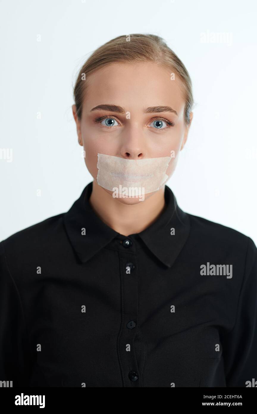 Portrait of woman with tape on mouth isolated on white studio background Stock Photo