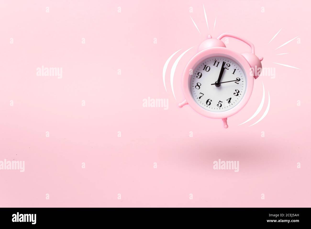 modern pink alarm clock falling on the floor with pink color background Stock Photo
