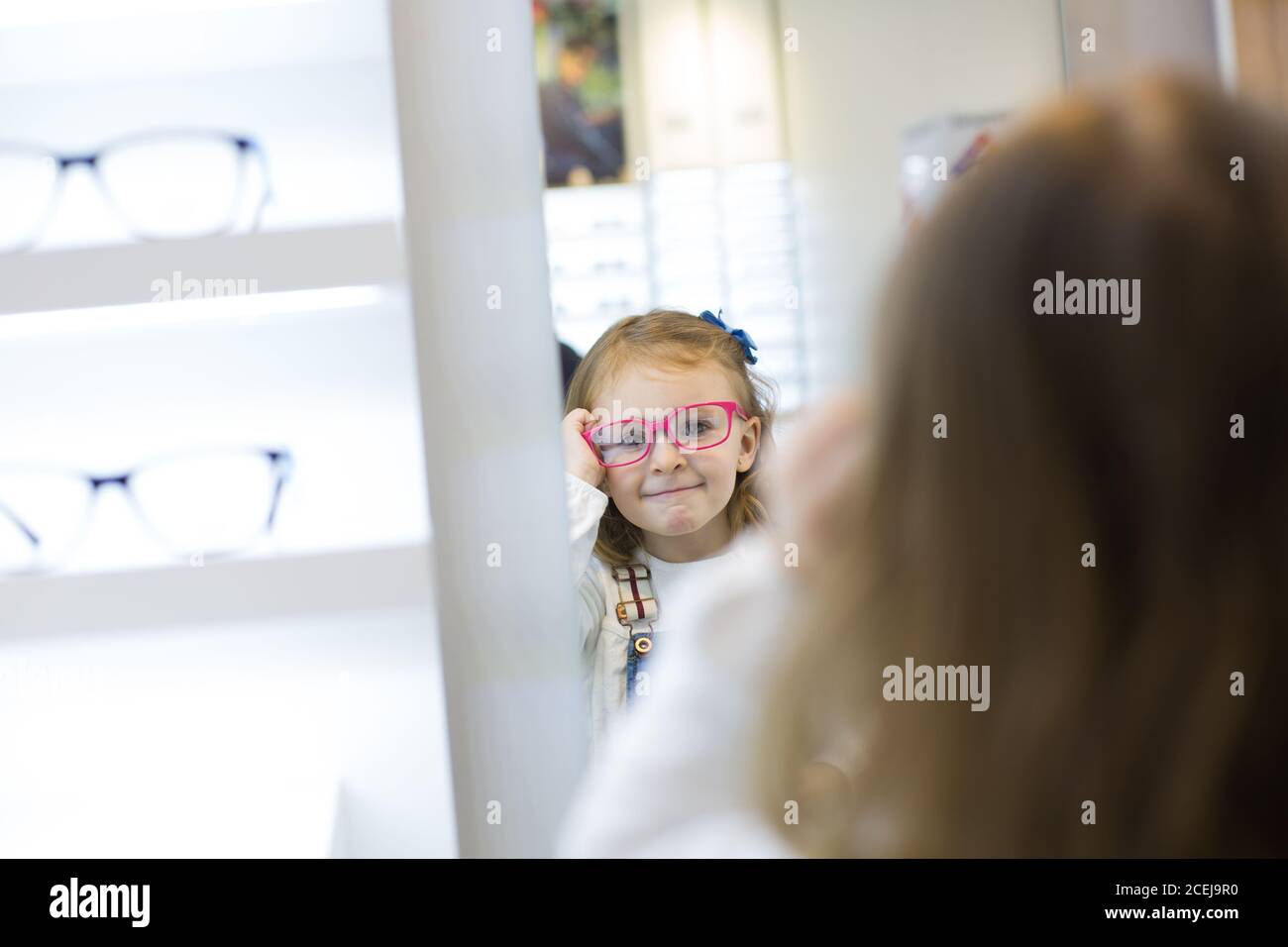 Cute young girl trying on glasses in an eyewear store Stock Photo Alamy
