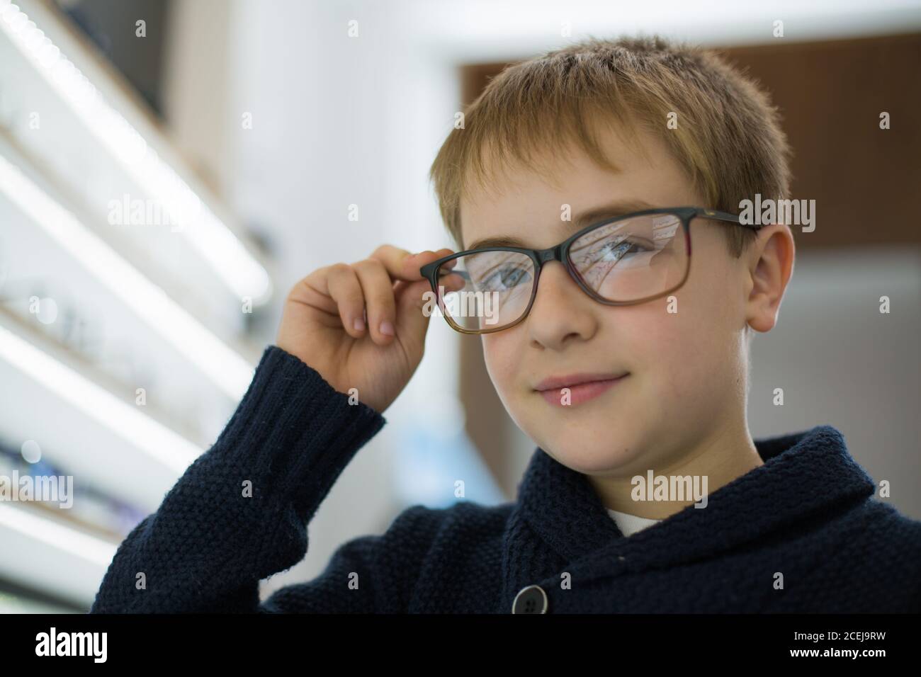 Cute young boy trying on glasses in an eyewear store Stock Photo Alamy
