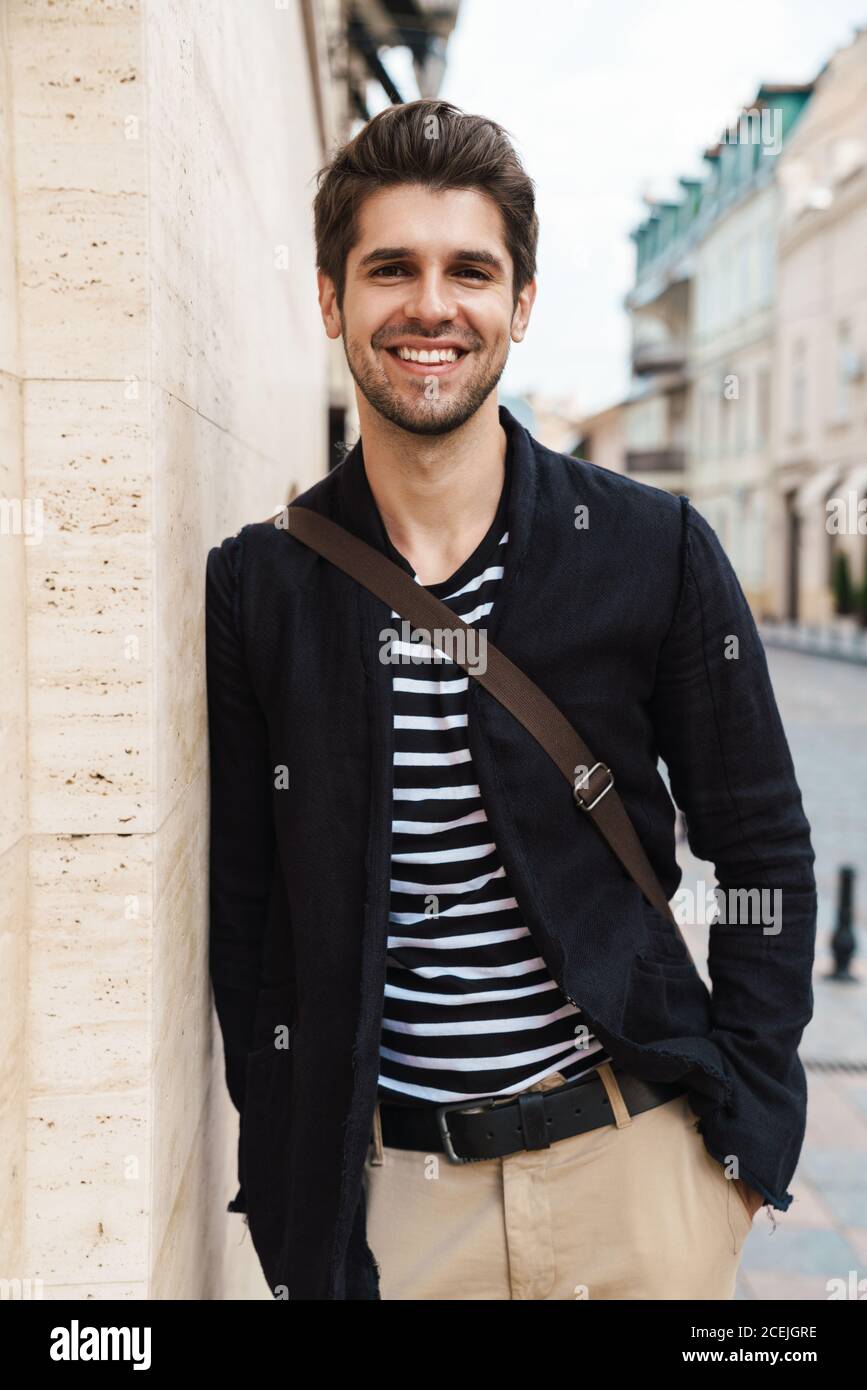 Photo of a cheerful young business man walking by street outdoors Stock