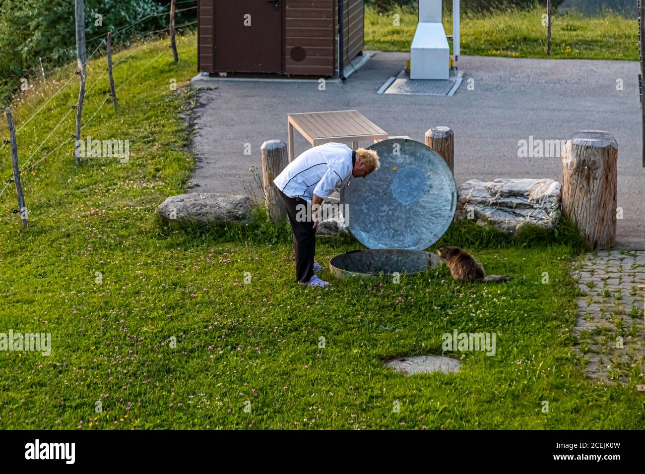 Gunter Steininger checks the underground pipe system and is assisted by his cat. He is chef of the mountain restaurant Bühlberg which is a dependence of Hotel Lenkerhof, Lenk, Switzerland Stock Photo