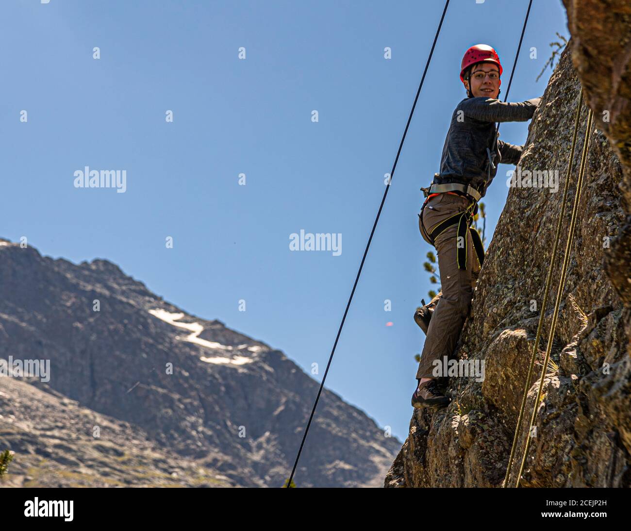 Young man roping down a rock in front of Piz Palü. Abseiling in front of the massif of Piz Palü is the reward at the end of the introductory climbing course. Rockclimbing in Pontresina, Switzerland Stock Photo