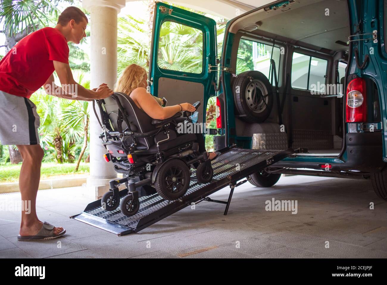 Driver assisting disabled person on wheelchair with transport using