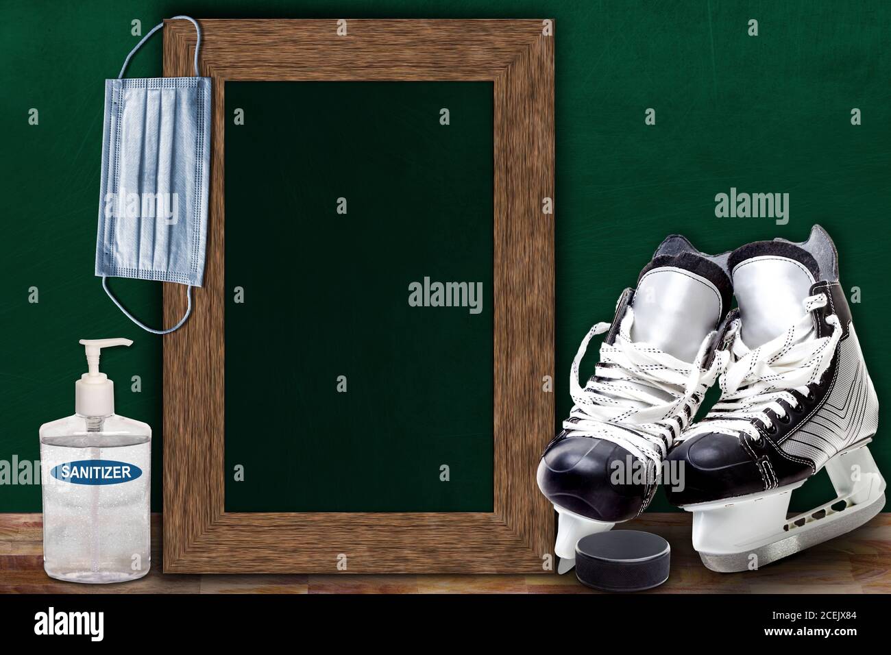 COVID-19 new normal sports concept in a classroom setting showing framed chalkboard with copy space and ice hockey skates and puck on wooden table. Stock Photo