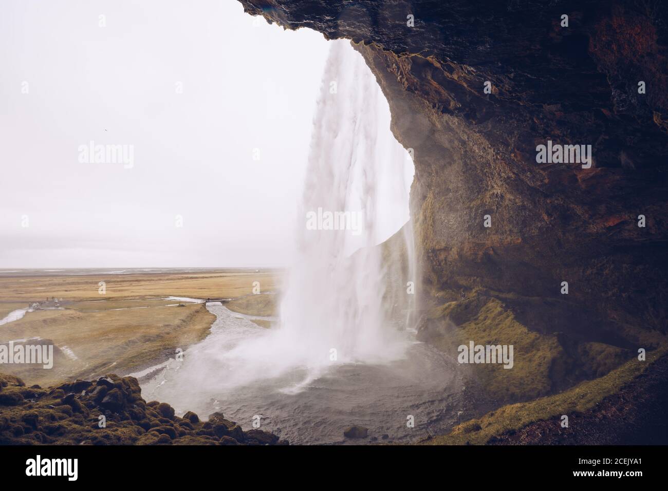Cavern with water cascade falling in river streaming between wild lands in Iceland Stock Photo