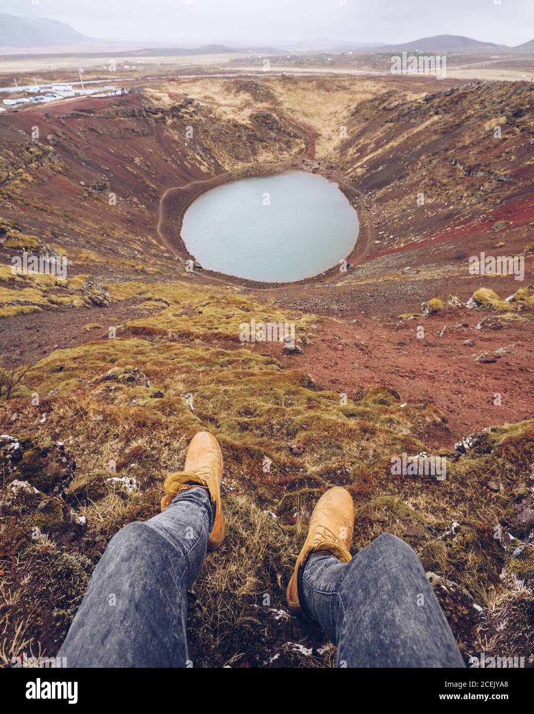 From above crop human legs near lake in crater between death brown lands and hills in Iceland Stock Photo