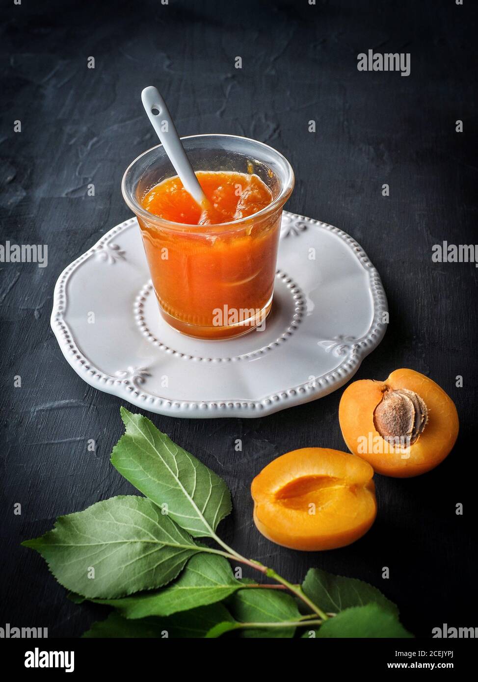 Fresh apricot cut in half with apricot jam on dark background. Dark food photo with copy space. Stock Photo