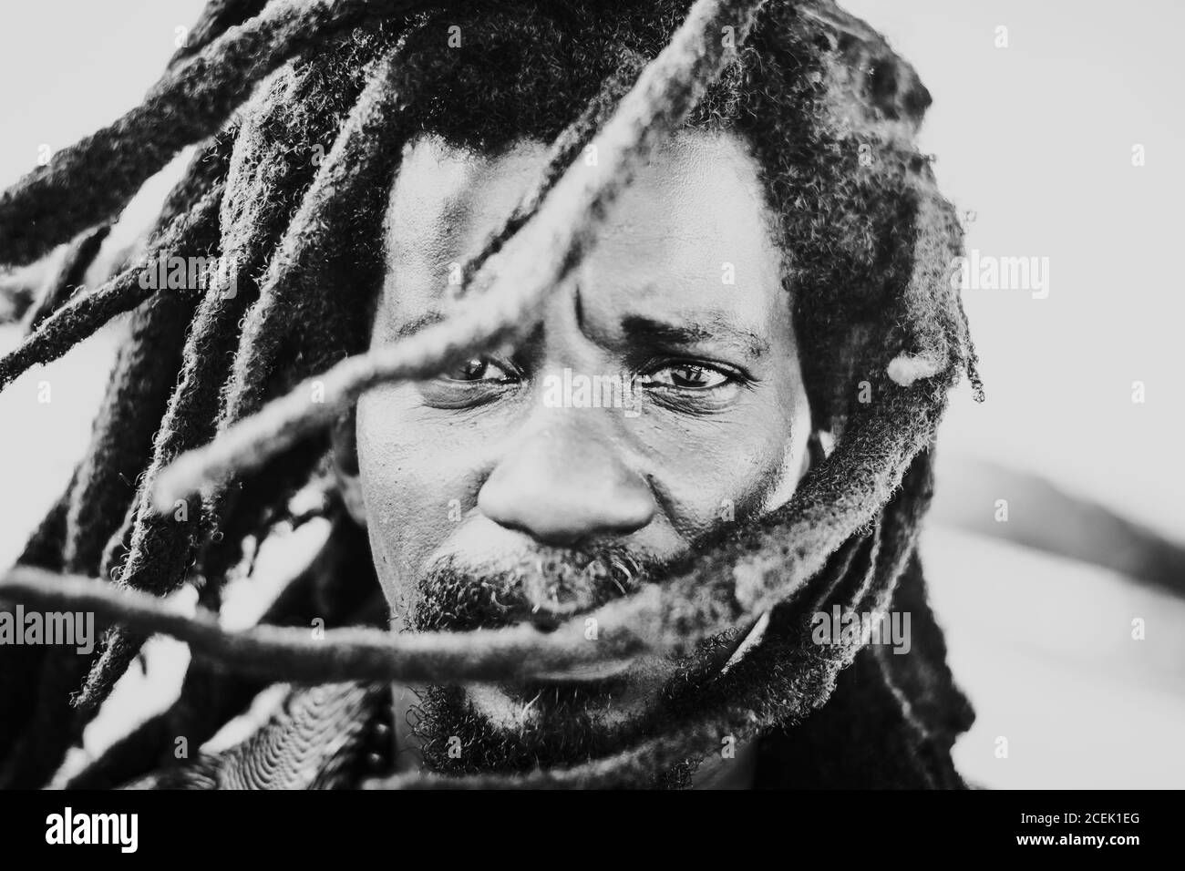 LA HABANA, CUBA - MAY 1, 2018: Black and white shot in close-up of ethnic serious man with dreadlocks flying in wind looking at camera. Stock Photo