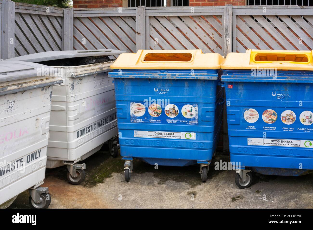 Communal refuse and recycling bins for household waste and recycling rubbish for collection outside flats in Winterthur Way, Basingstoke, UK. Stock Photo