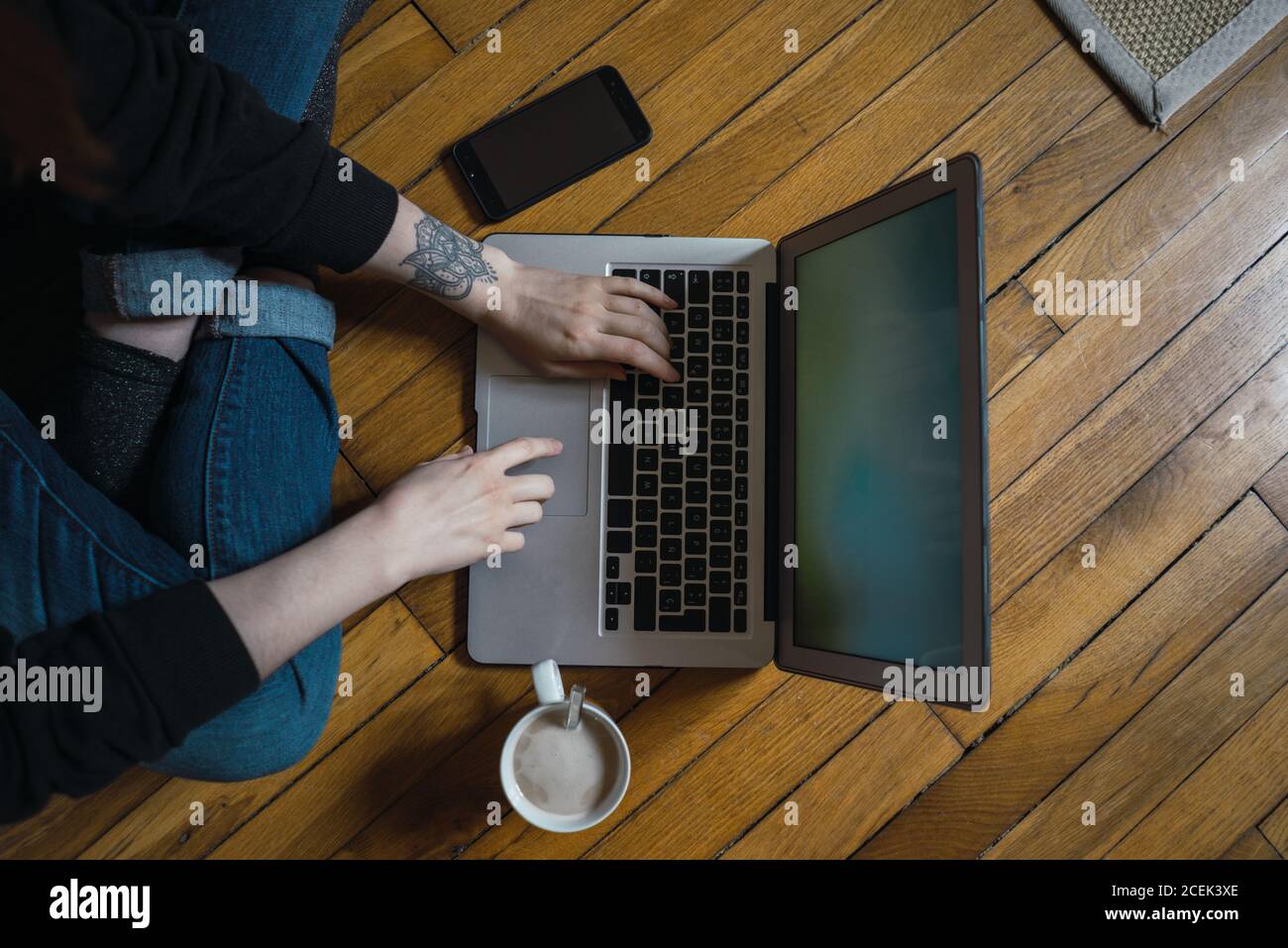 Crop Woman typing on laptop on floor Stock Photo