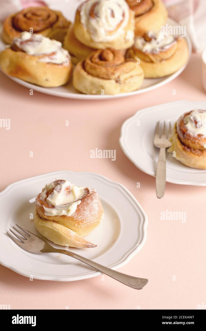 Ceramic plates with delectable buns and fork standing on peach tabletop Stock Photo
