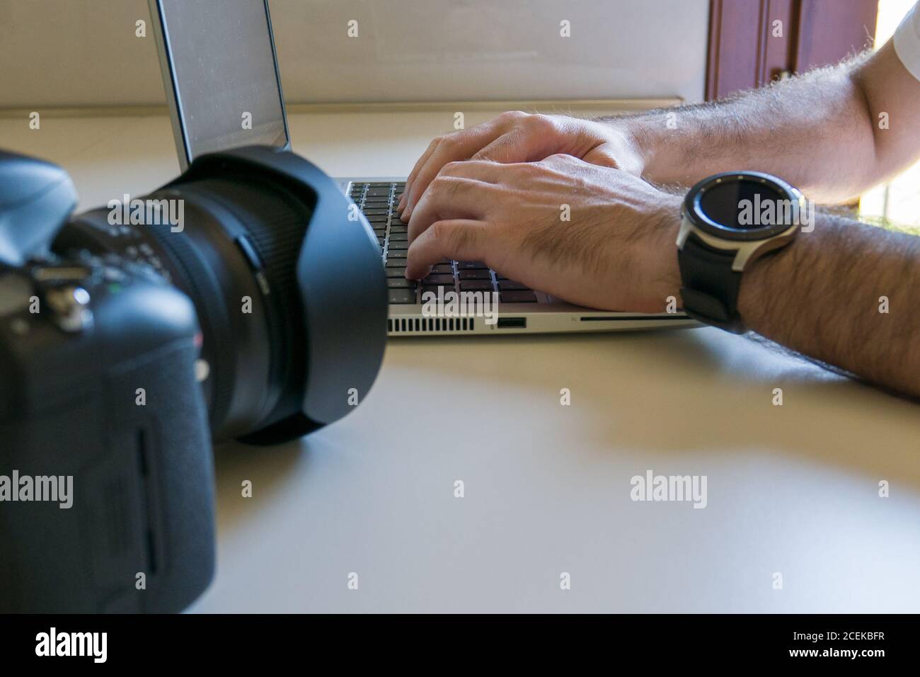 man processes photos on laptop after downloading them from camera Stock Photo