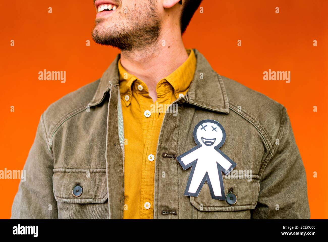 Crop happy guy with paper silhouette for April fools day on jean jacket on orange background Stock Photo
