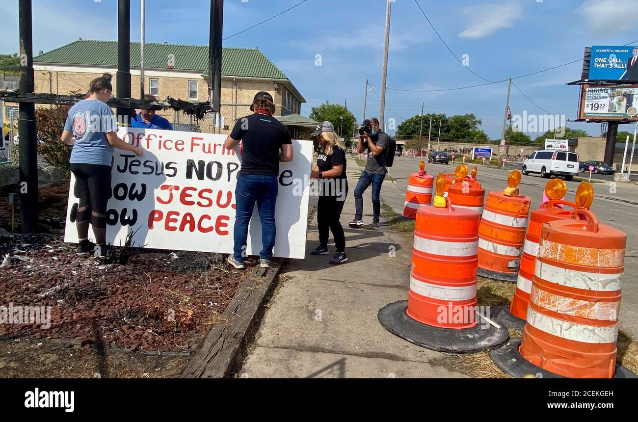 Kenosha, Wisconsin, USA. 31st Aug, 2020. One day before President Trump visited B&L Office Furniture owner Scott Carpenter's burnt out store, a group of people from out of town showed up and gifted him a sign that reads, 'No Jesus, No Peace, Know Jesus, Know Peace'', which is a controversial play on words, as 'No Justice, No Peace'' is the most often chanted slogan at Black Lives Matter protests. His store was set on fire in the aftermath of the shooting of a black man by a Kenosha Police officer. After they got the sign up, they said a prayer and hugged. Carpinter said in an interv Stock Photo