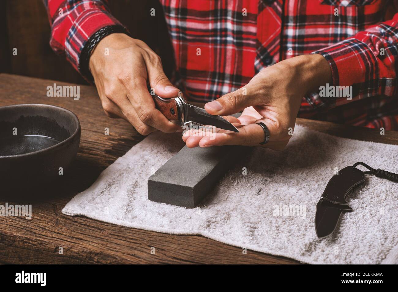 The man using whetstone to sharpening his pocket knife. Pocket knife