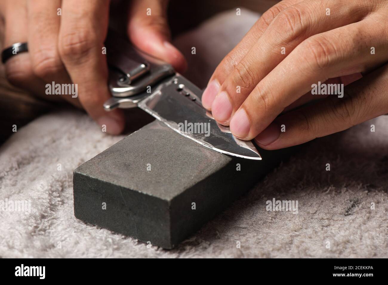 The man using whetstone to sharpening his pocket knife. Pocket knife