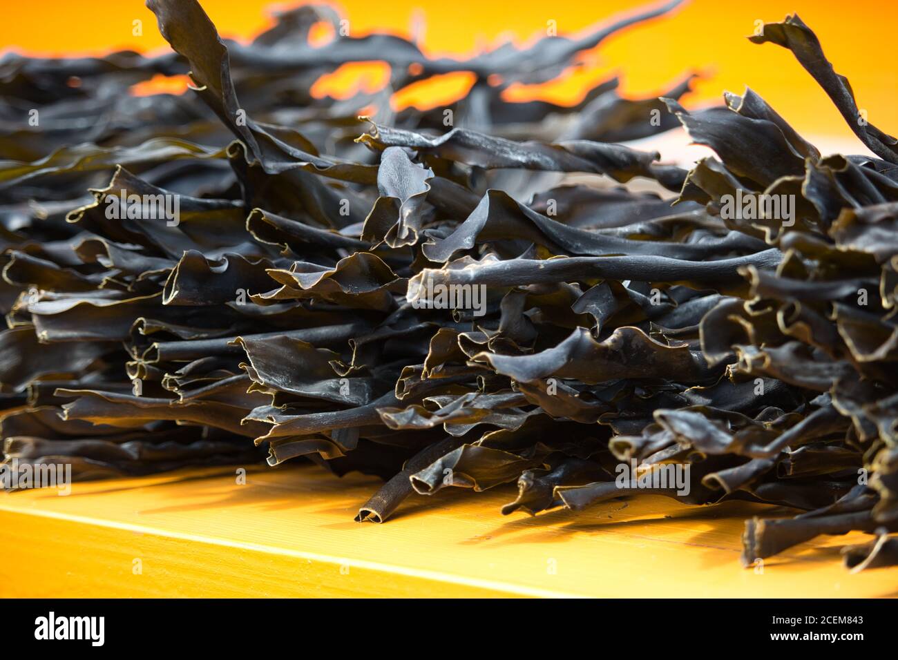 Loose, dry kombu kelp seaweed unwrapped and neatly stacked on an orange table / background Stock Photo