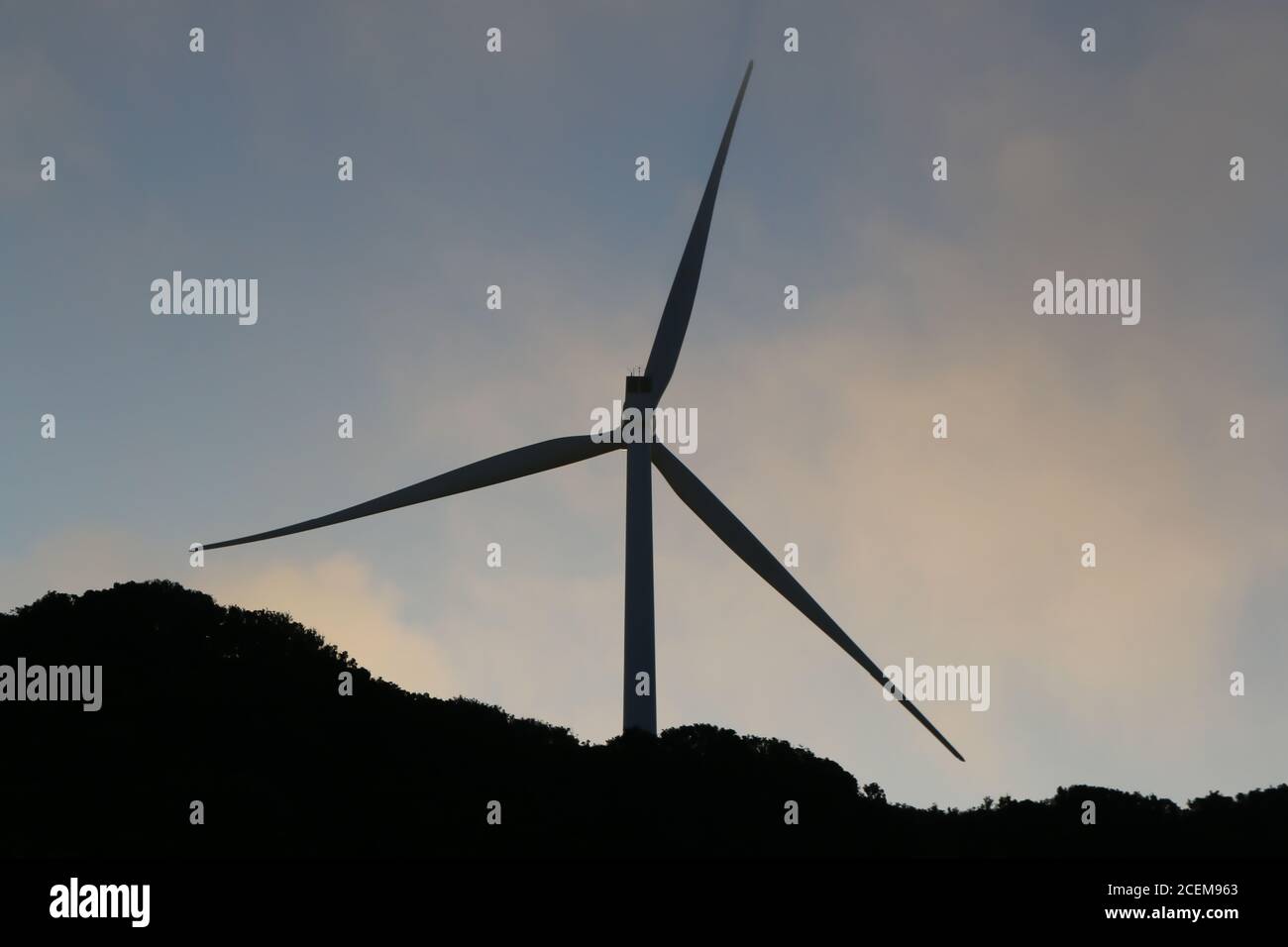 Blades of a wind turbine silhouetted in the mist against a pink morning sunrise Stock Photo