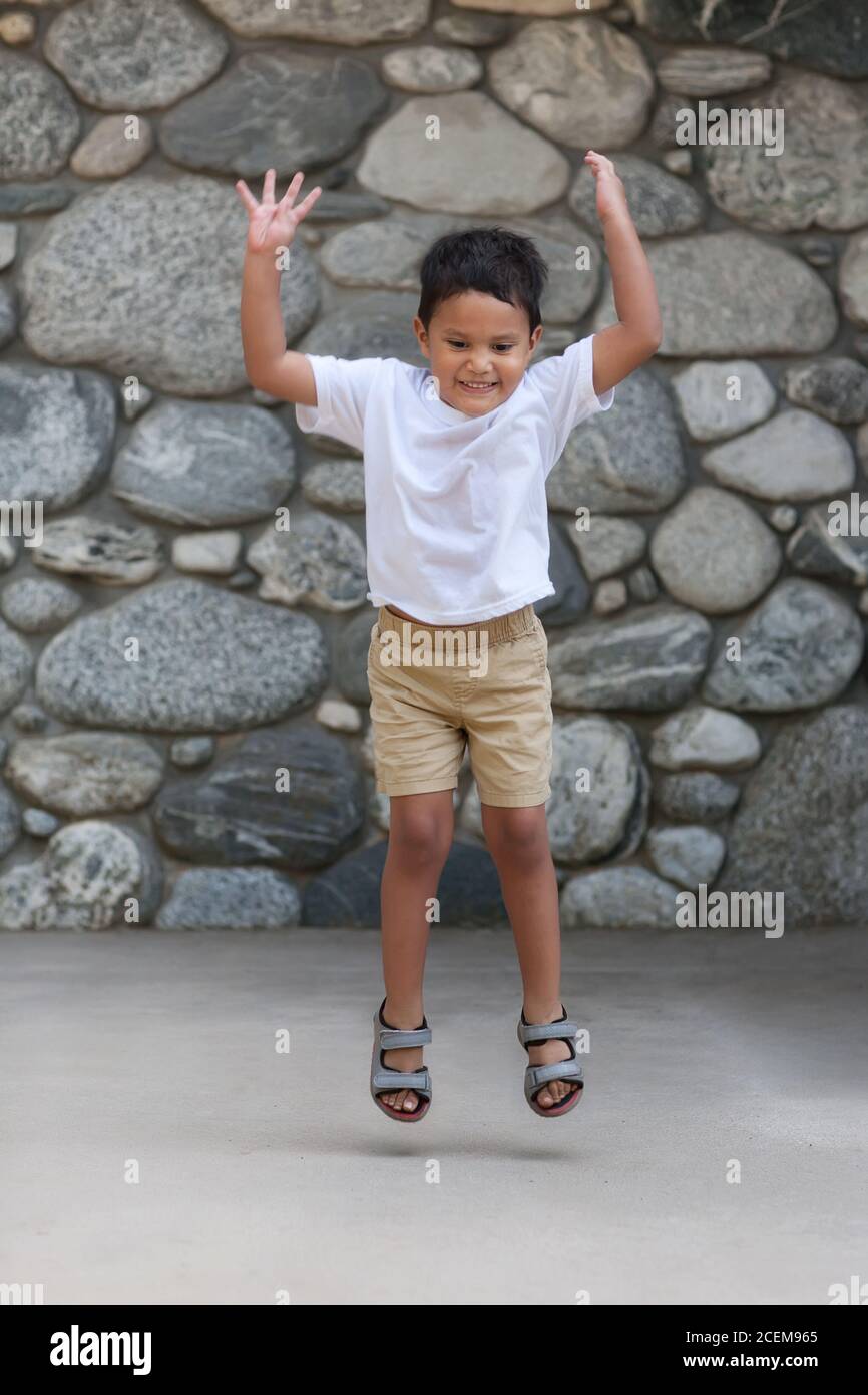 A healthy four year old boy tries to jump as high off the ground as he can. Stock Photo