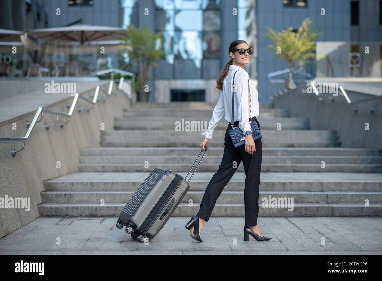 Dark-haired stylish woman walking down the street Stock Photo
