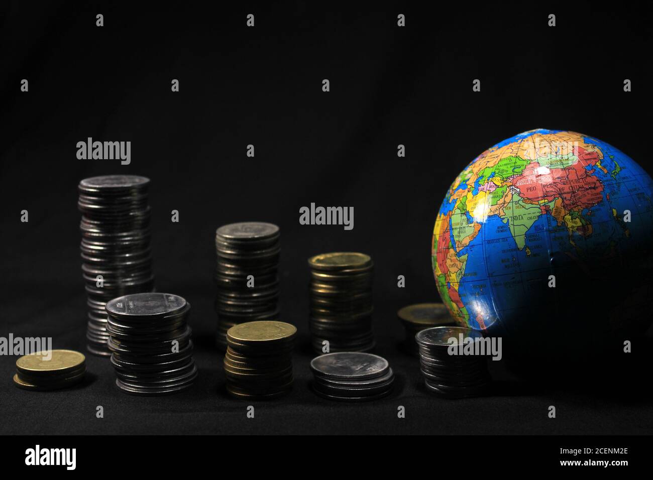Stock pile of 1, 2, 5, 10 Indian rupee metal coin currency with globe isolated on black background. Financial, economy, investment concept. Stock Photo