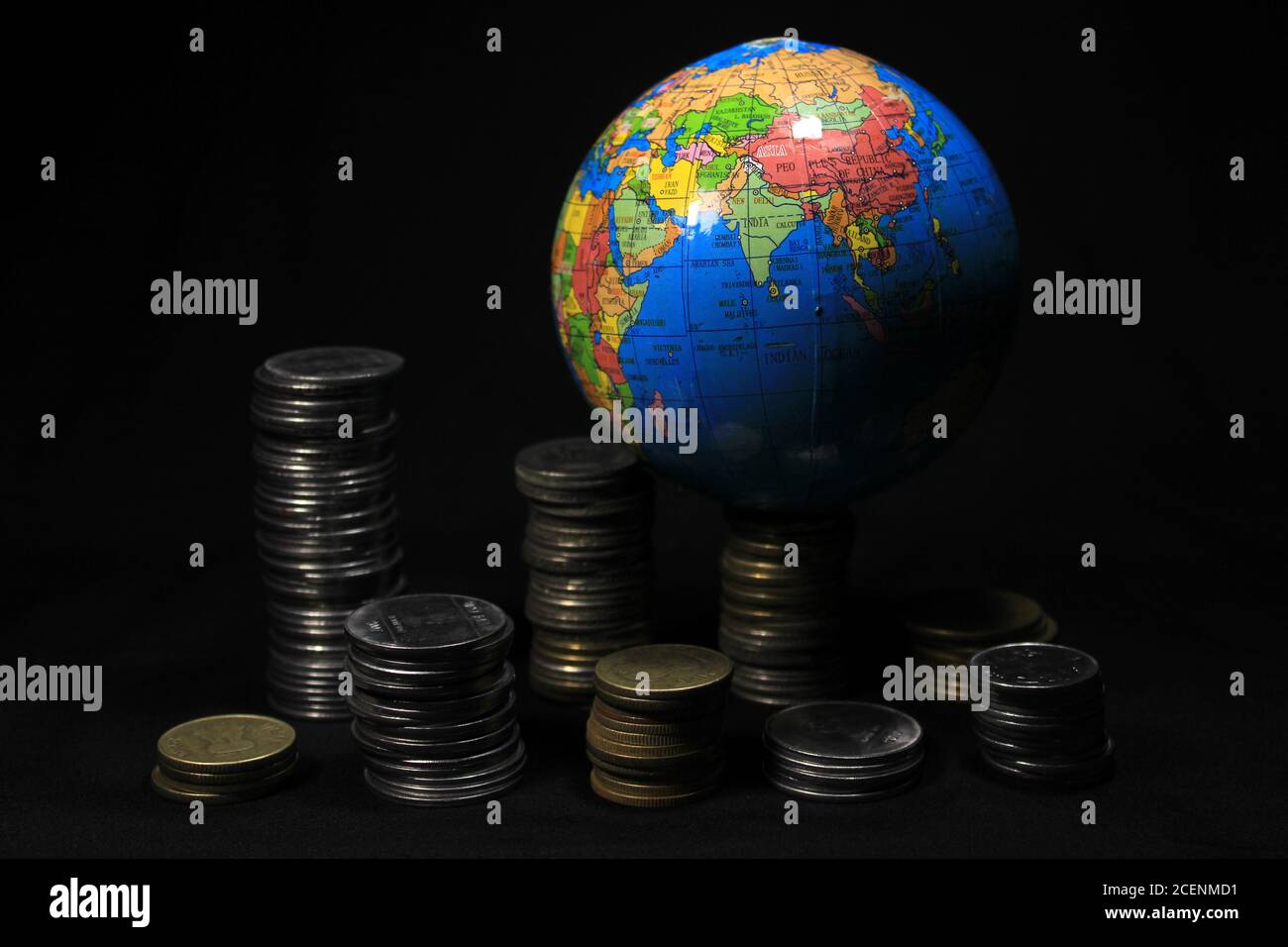 Stock pile of 1, 2, 5, 10 Indian rupee metal coin currency with globe isolated on black background. Financial, economy, investment concept. Stock Photo