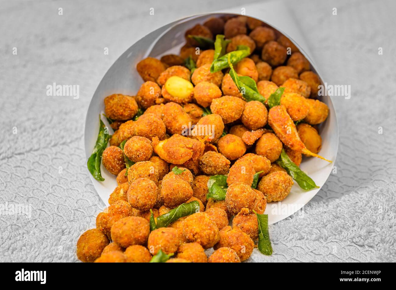 Traditional Indian snack - Masala Peanuts with Fried Curry Leaves in a Paper Cone Stock Photo