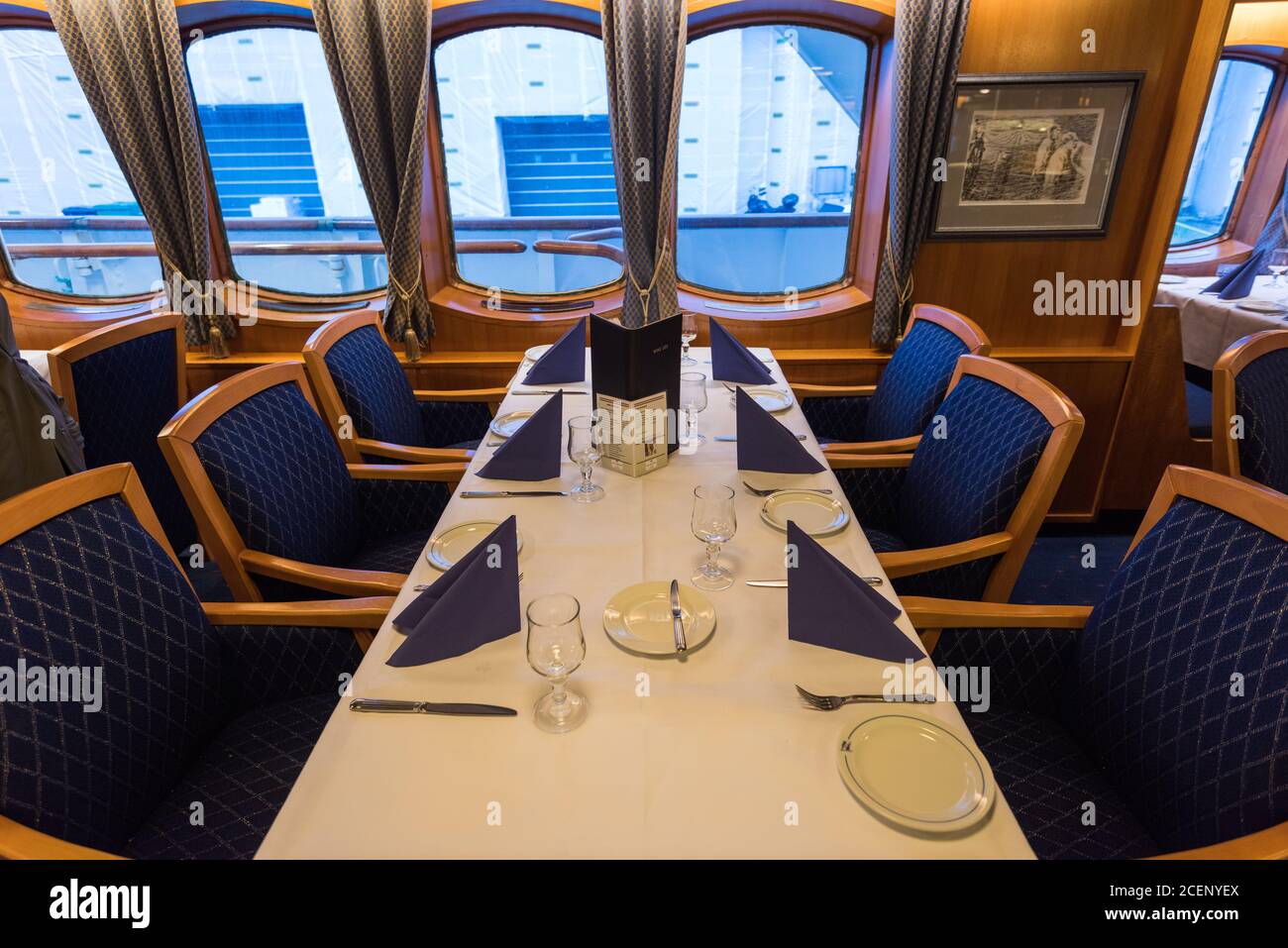 Laid table for six persons in dining salon on the coastal cruise ship MS Lofoten of norwegian mailboat line Hurtigruten lying in the port of Bergen Stock Photo